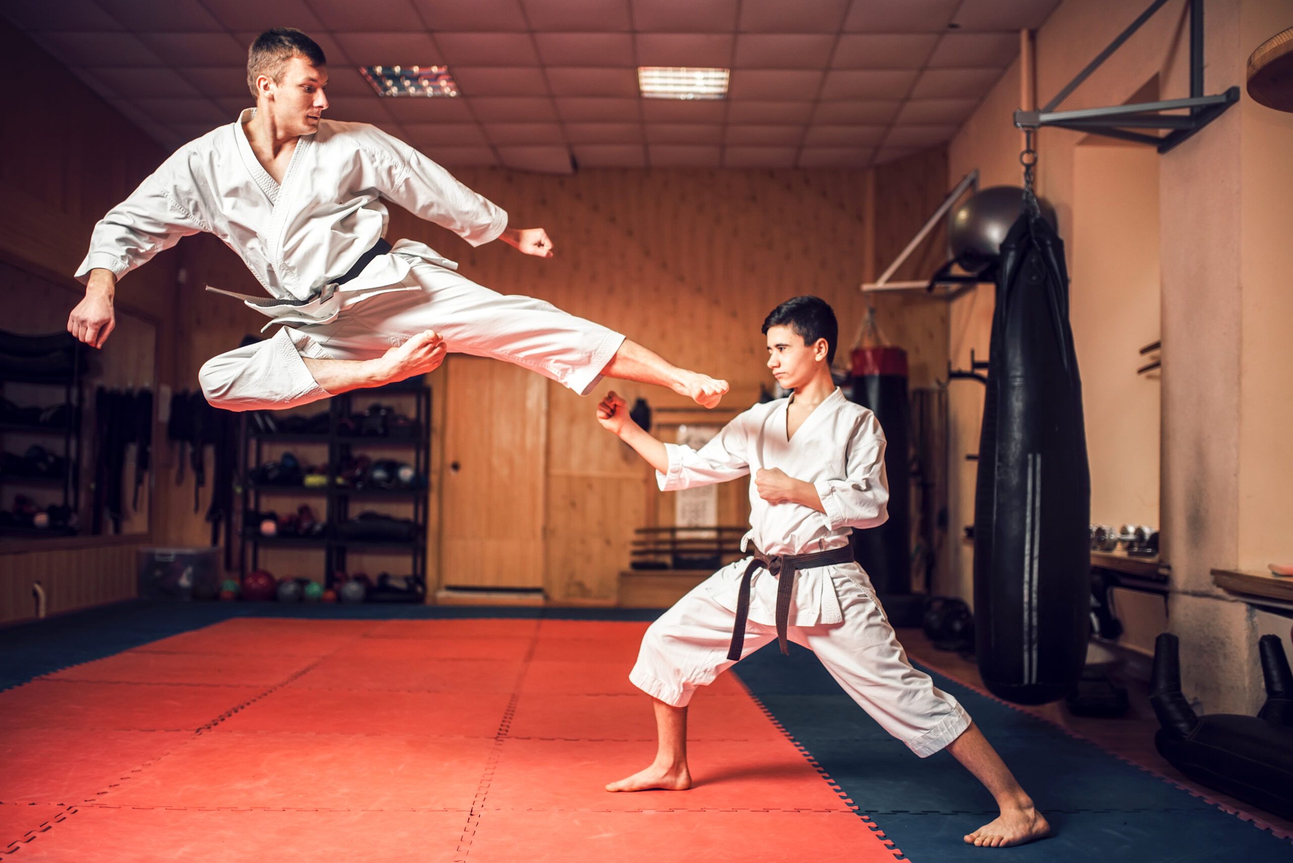 Entrenamiento de Karate: Patada y Defensa en Acción Dos practicantes de karate, uno lanzando una patada y el otro defendiéndose con precisión durante un entrenamiento.